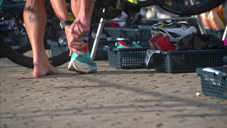 Slow-motion-close-up-of-a-male-athlete-ending-the-cycling-stage-at-a-triathlon-preparing-for-the-running-stage-putting-on-his-running-shoes