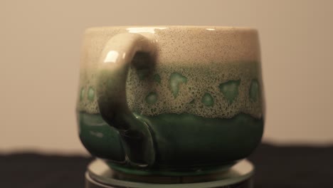Close-Up-Shot-Of-Homemade-Ceramic-Green-Mug-Displayed-On-Turntable-Platform