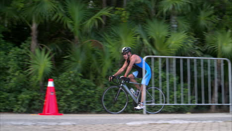 Zeitlupe-Eines-Männlichen-Athleten,-Der-Einen-Blauen-Anzug-Trägt,-Der-Sein-Fahrrad-Auf-Der-Radsportbühne-Eines-Triathlons-Fährt