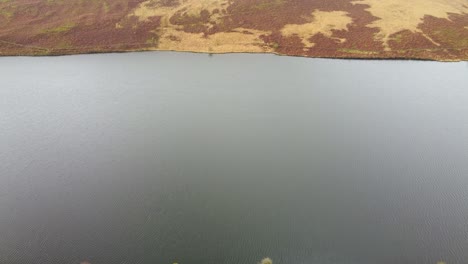 Pushing-Aerial-Drone-Shot-Over-Reservoir-with-Moorland-and-Hiker-Path-4K