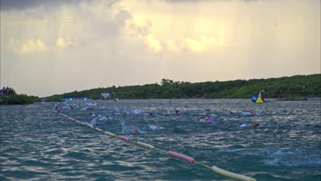 Slow-motion-of-a-big-group-of-athletes-swimming-competing-in-a-triathlon-in-the-sea-early-in-the-morning