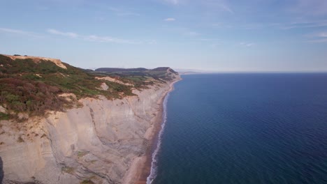 High-drone-shot-moving-backwards-along-the-cliffs-on-the-Jurassic-Coast-on-a-summer-day,-Dorset,-UK