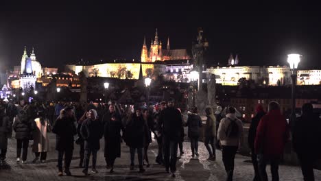 Crowds-strolling-on-Charles-bridge-at-night-below-Prague-castle