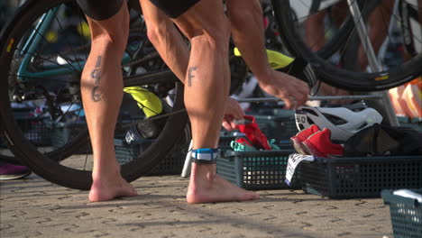 Zeitlupe-Nahaufnahme-Eines-Männlichen-Athleten,-Der-Die-Radetappe-Bei-Einem-Triathlon-Beendet-Und-Sich-Auf-Die-Laufetappe-Im-Wechselbereich-Vorbereitet