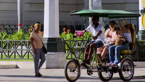 Tourists-take-a-bicycle-taxi-in-Havana,-Cuba