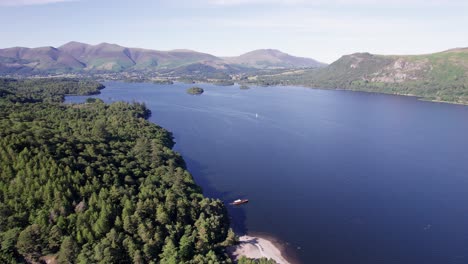 High-drone-shot-flying-right-over-Derwent-Water-with-boats-on-the-lake-on-a-sunny-day,-Lake-District,-Cumbria,-UK