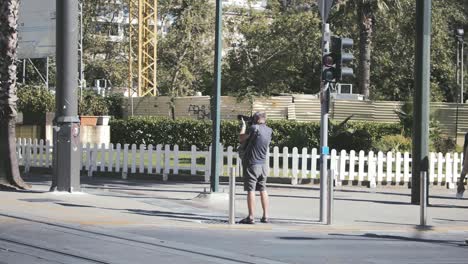 Male-tourist-with-a-camera-taking-photos-and-videos-in-the-street