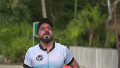 Slow-motion-of-a-male-triathlon-athlete-finishing-the-competition-running-looking-happy-wearing-glasses