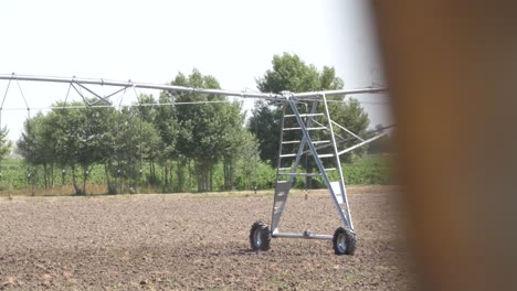 Side-view-pivot-at-work-in-potato-field,-watering-crop-for-more-growth