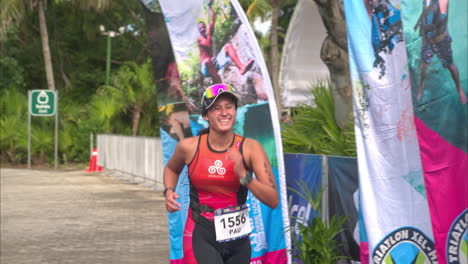 Slow-motion-of-a-female-triathlon-athlete-finishing-the-competition-smiling-looking-exhausted