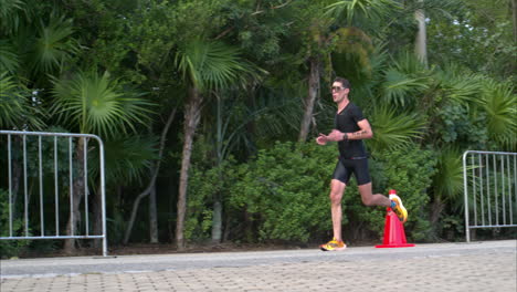 Slow-motion-of-a-male-athlete-wearing-a-black-suit-competing-at-the-running-stage-of-a-triathlon