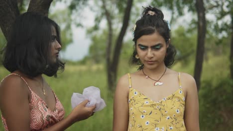 A-slow-motion-shot-of-two-carefree-Asian-females-in-a-forest-dressing-each-other-up-applying-a-pretty-decorative-hair-band-accessory,-India