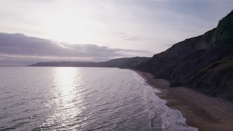 Drone-shot-flying-forward-along-the-beach-on-the-Jurassic-Coast-on-a-Summer-evening,-Dorset,-UK