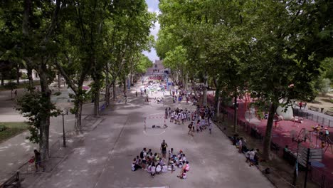 Aerial-view-over-park-in-Montpellier,-France-with-school-kids-sitting-on-the-football-field