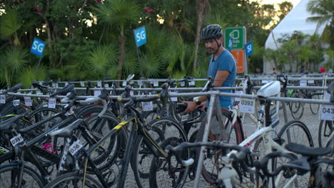 Atleta-Latino-Masculino-Con-Casco-Colocando-Su-Bicicleta-En-El-Punto-De-Transición-Preparándose-Para-Una-Competencia-De-Triatlón