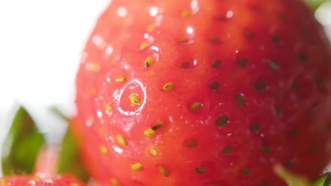 Extreme-close-up-of-water-drops-splashing-on-a-fresh-Strawberry,-Slow-motion-shot