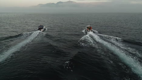 Dos-Barcos-Navegando-Al-Atardecer-Hacia-Una-Isla-Con-Un-Volcán