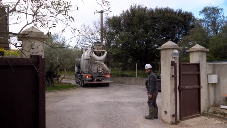 Construction-worker-trying-to-help-the-driver-park-the-cement-truck-through-the-gate