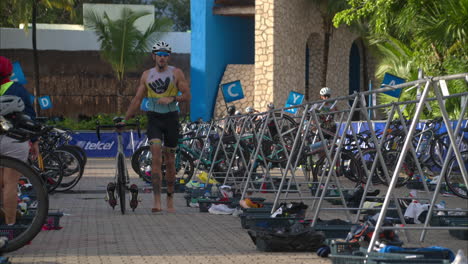 Slow-motion-of-a-male-athlete-running-along-his-bike-barefoot-finishing-the-cycling-stage-entering-the-transition-zone-in-a-triathlon