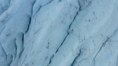 top-down-rising-aerial-shot-of-ridged-and-textured-ice-sheet-of-a-glacier