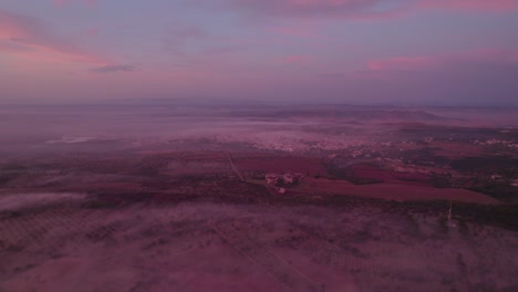 Rural-Italy-with-low-hanging-clouds-during-pink-sunrise,-aerial