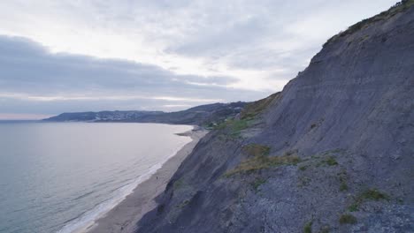 Drone-shot-flying-backwards-along-a-cliff-face-on-the-Jurassic-Coast,-Dorset,-UK