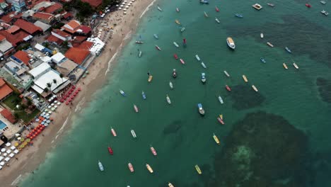 Bird's-eye-top-down-aerial-drone-wide-shot-of-the-Porto-de-Galinhas-or-Chicken-Port-beach-with-dozens-of-anchored-sailboats-and-tourists-swimming-in-the-crystal-clear-ocean-water-in-Pernambuco,-Brazil