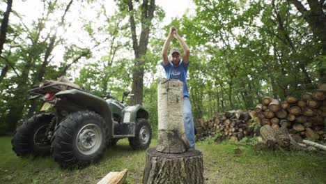Man-with-hat-splitting-wood-log-in-the-woods-in-front-of-atv-slow-motion