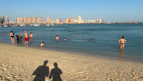 Shadow-of-a-couple-standing-in-the-beach-in-Doha-Qatar-landscape-of-family-friend-and-woman-stand-enjoy-the-sea-landscape-towers-of-the-city-and-beautiful-scenic-background-nice-swimming-in-freedom