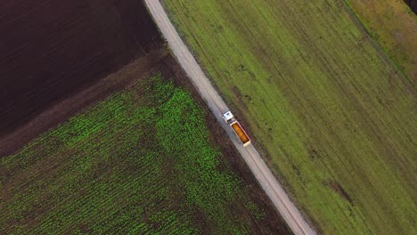 Aerial-View-Of-Loaded-Truck-Driving-On-Country-Road-Through-Cultivated-Fields