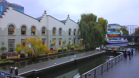 High-angle-shot-over-Regent's-canal-in-Camden-area-in-London,-UK-on-a-cloudy-day-with-tourists-looking-the-beautiful-architecture