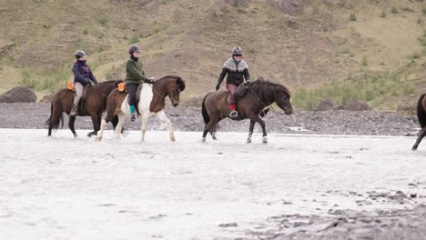 Group-of-tourist-on-horses-riding-through-shallow-water-in-Thórsmörk-valley