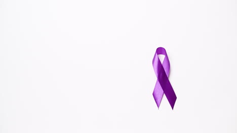 Detail-of-male-hand-placing-ribbon-in-purple-color-over-white-background