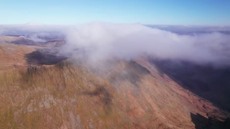 Drone-shot-pulling-backward-through-clouds-above-a-mountain,-Helvellyn,-Lake-District,-Cumbria,-UK
