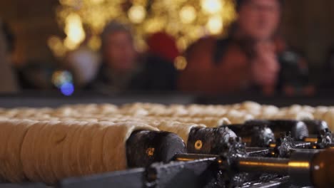 Rolling-trdelnik-closeup-and-people-in-Christmas-Prague,-traditional-street-food-of-Czech-Republic