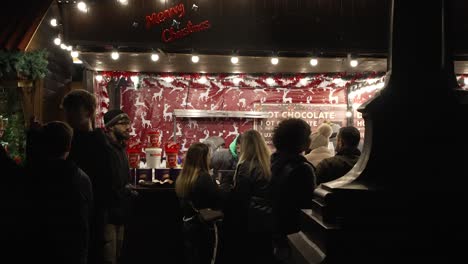 Sillhouute-Von-Menschen,-Die-Nachts-In-London-An-Einem-Stand-Mit-Heißer-Schokolade-Auf-Den-Trafalgar-Square-Weihnachtsmärkten-Vorbeigehen