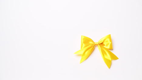 Detail-of-male-hand-holding-ribbon-in-yellow-color-on-white-background