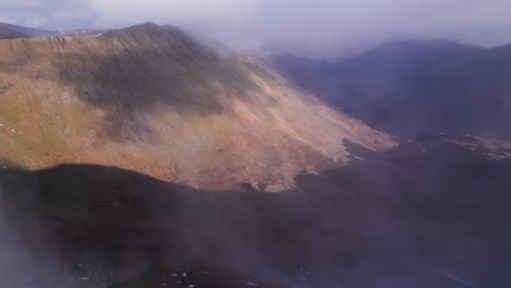 Drone-shot-flying-forward-through-clouds-to-reveal-landscape-below,-Helvellyn,-Lake-District,-Cumbria,-UK