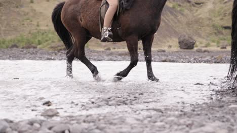 Horse-tour-going-through-shallow-glacial-river-splashing-water,-Iceland