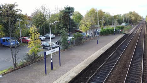 British-town-train-station-car-parking-panning-to-long-railway-lines-off-to-skyline