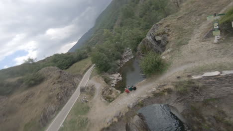 Epic-fast-FPV-drone-flying-above-river-stream-then-rises-above-bridge-and-under