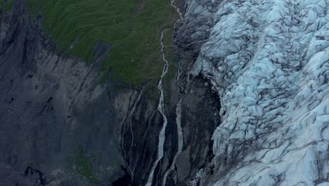 Waterfall-melt-water-flowing-from-Icelandic-glacier,-Virkisjökull,-aerial