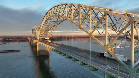 Welcome-to-Arkansas-sign-on-Hernando-de-Soto-bridge-over-Mississippi-River-with-barge-below