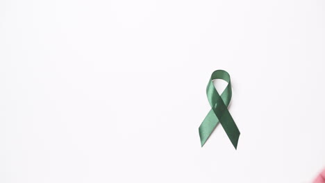 Detail-of-male-hand-putting-green-ribbon-over-white-background