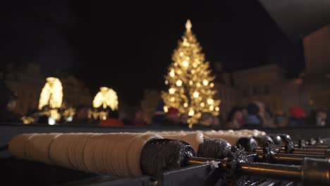 Trdelnik-and-Christmas-tree-in-Prague,-people-in-background,-Czech-Republic-market