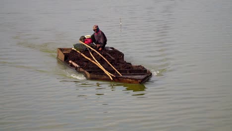 Toma-En-Cámara-Lenta-De-Un-Pescador-Masculino-Cruzando-El-Lago-Rawa-Pening-Con-Un-Bote-De-Madera-Tradicional-En-Java-Central,-Indonesia