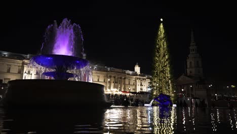 Weihnachtsbaum-Auf-Dem-Trafalgar-Square-Mit-Festlichen-Marktlichtern,-Die-Sich-In-Springbrunnen-Spiegeln