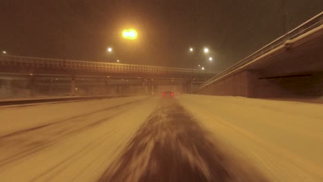 POV-following-shot-of-traffic-passing-under-a-highway-bridge-in-heavy-snow