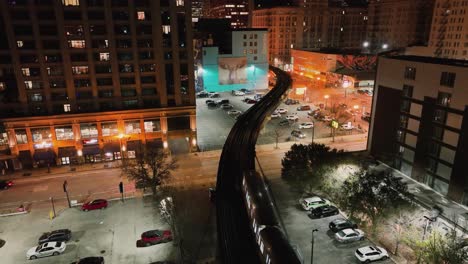 CTA-train-on-a-elevated-rails-in-middle-of-buildings-in-illuminated-South-Loop,-Chicago,-USA---Aerial-view