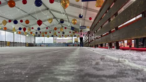 Kleines-Süßes-Mädchen,-Das-Allein-Auf-Eis-In-Einer-Leeren-Indoor-Eisbahn-Mit-Weihnachtsdekorationen-Eisläuft